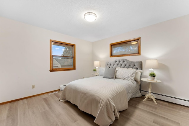 bedroom featuring baseboards, baseboard heating, and light wood-style floors