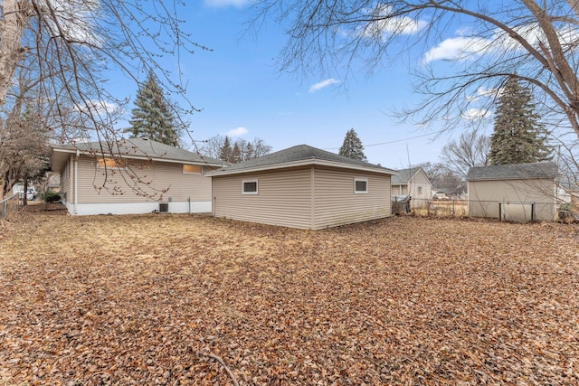 rear view of property with an outbuilding and fence