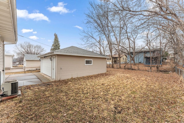 view of yard with an outbuilding, central AC unit, a garage, fence, and a trampoline