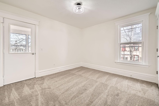 spare room with carpet floors, baseboards, and a textured ceiling