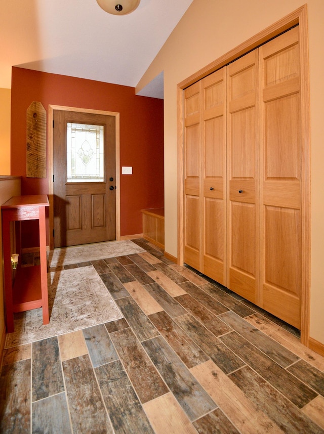 entrance foyer featuring lofted ceiling, baseboards, and wood finished floors