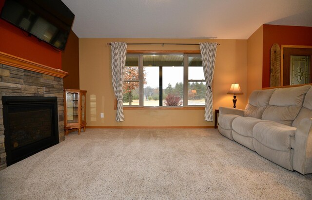 carpeted living room featuring baseboards and a stone fireplace