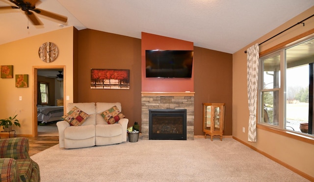 carpeted living area featuring vaulted ceiling, a stone fireplace, plenty of natural light, and baseboards