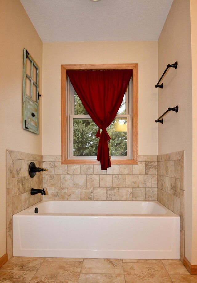 bathroom featuring baseboards and a bath