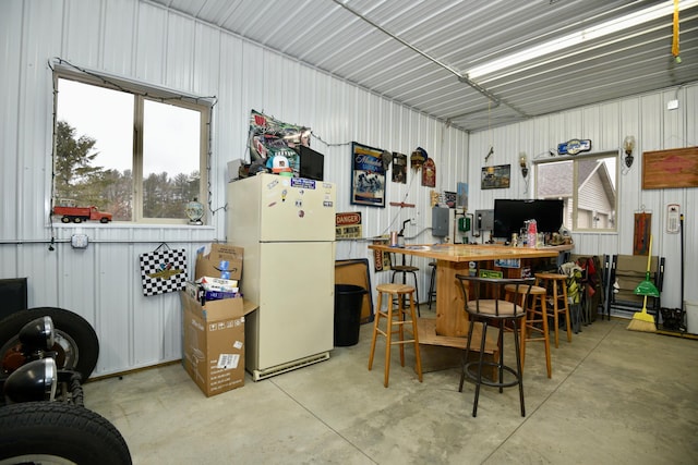 kitchen with freestanding refrigerator, concrete floors, and metal wall