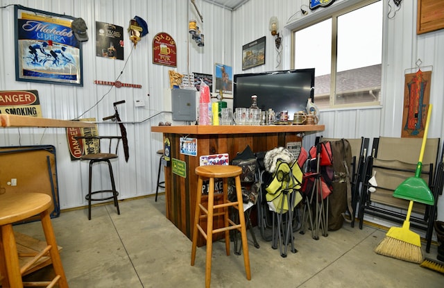 misc room with concrete flooring, a bar, and metal wall