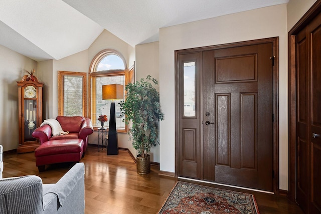 foyer entrance with lofted ceiling, wood finished floors, and baseboards