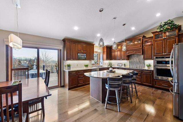 kitchen featuring lofted ceiling, stainless steel appliances, decorative backsplash, and a center island