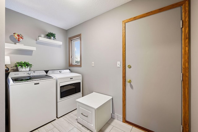 washroom featuring laundry area, washing machine and dryer, baseboards, and a textured ceiling