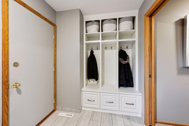 mudroom featuring baseboards, visible vents, and wood finish floors