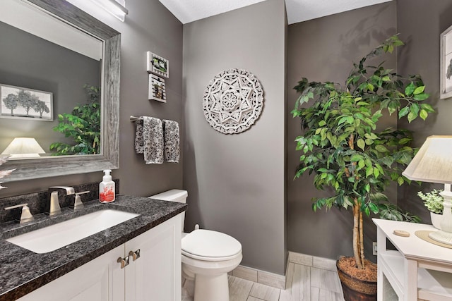 bathroom with vanity, toilet, and baseboards