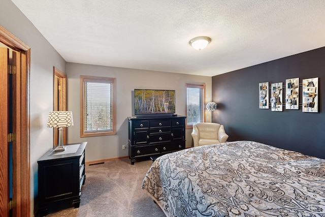 carpeted bedroom featuring visible vents, a textured ceiling, and baseboards