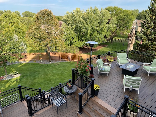 wooden deck featuring a fire pit, a lawn, and fence