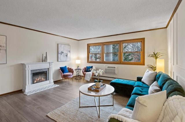 living area with a glass covered fireplace, ornamental molding, a wall unit AC, and wood finished floors