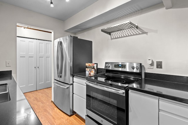 kitchen with appliances with stainless steel finishes, white cabinets, dark countertops, and a sink