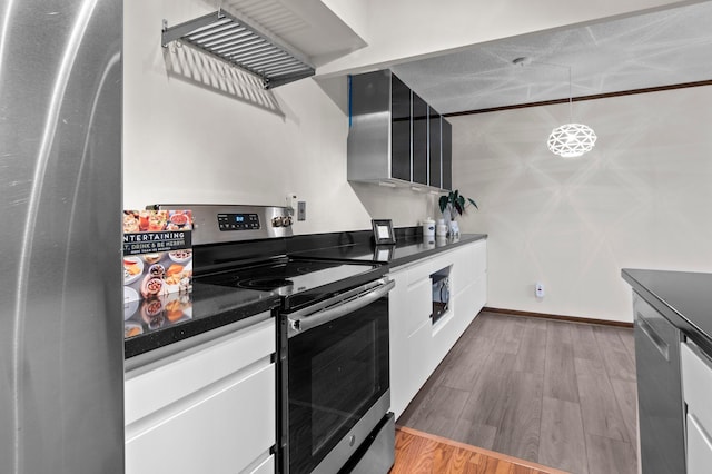 kitchen with stainless steel range with electric stovetop, dark countertops, wood finished floors, white cabinets, and baseboards