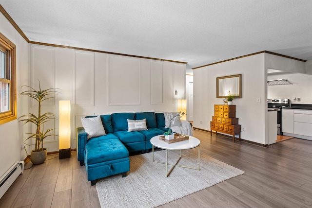 living area featuring baseboard heating, wood finished floors, crown molding, and baseboards