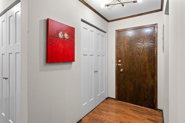foyer with ornamental molding and wood finished floors