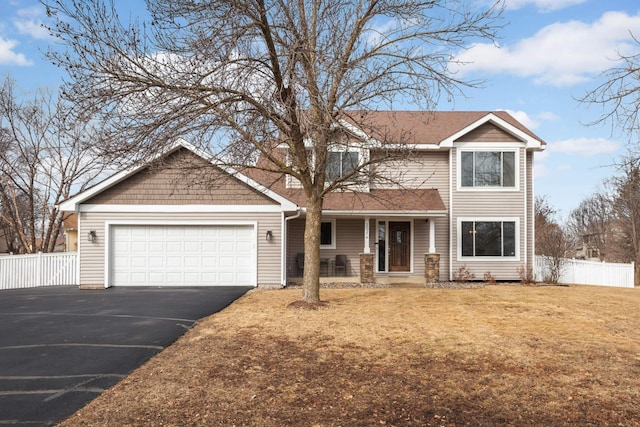 traditional home with aphalt driveway, an attached garage, covered porch, fence, and a front yard