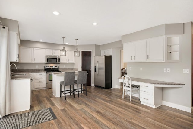 kitchen featuring dark wood finished floors, a breakfast bar area, stainless steel appliances, white cabinets, and a sink