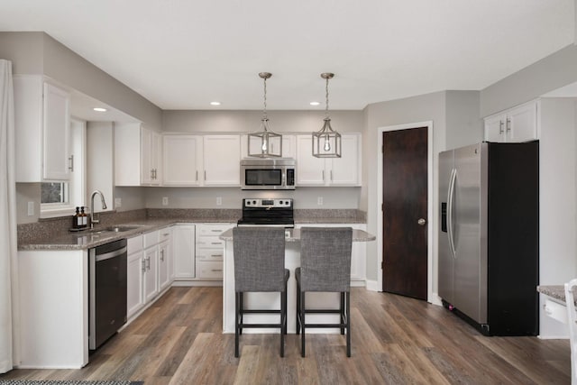 kitchen with a kitchen island, dark wood-type flooring, stainless steel appliances, white cabinetry, and a sink