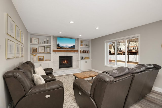 living room featuring baseboards, built in features, wood finished floors, a brick fireplace, and recessed lighting