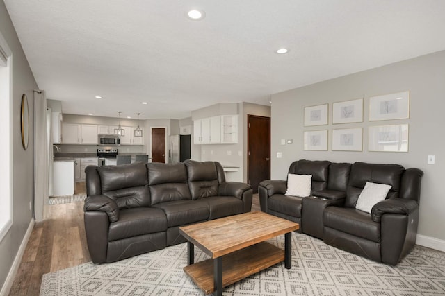 living area with light wood-style floors, baseboards, and recessed lighting