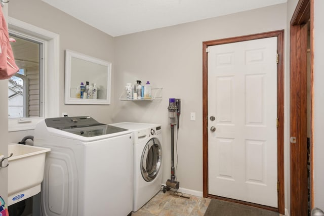 washroom with laundry area, a sink, baseboards, washer and dryer, and stone finish flooring