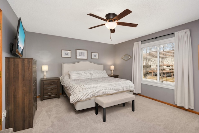 bedroom with a ceiling fan, light carpet, a textured ceiling, and baseboards