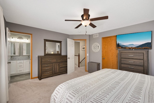 bedroom featuring ceiling fan, visible vents, ensuite bathroom, and light colored carpet