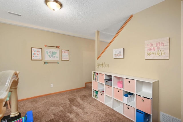 rec room with baseboards, a textured ceiling, visible vents, and carpet flooring