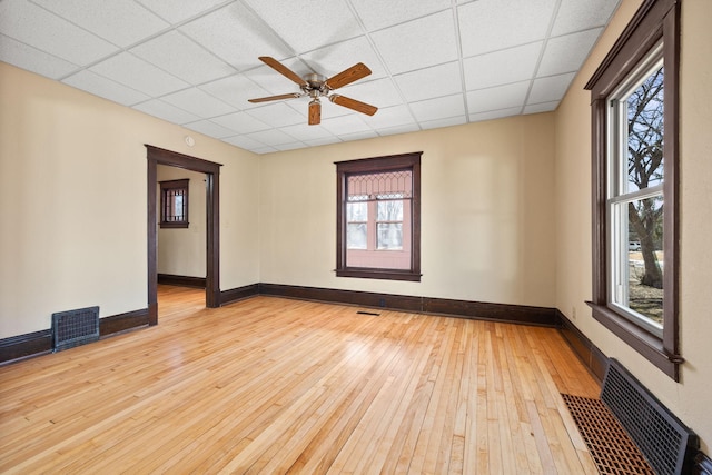 empty room with a paneled ceiling, hardwood / wood-style flooring, baseboards, and visible vents