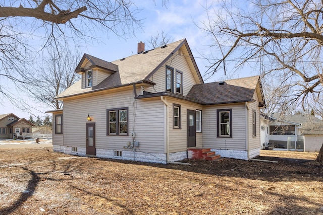 view of side of property featuring entry steps, a shingled roof, and a chimney