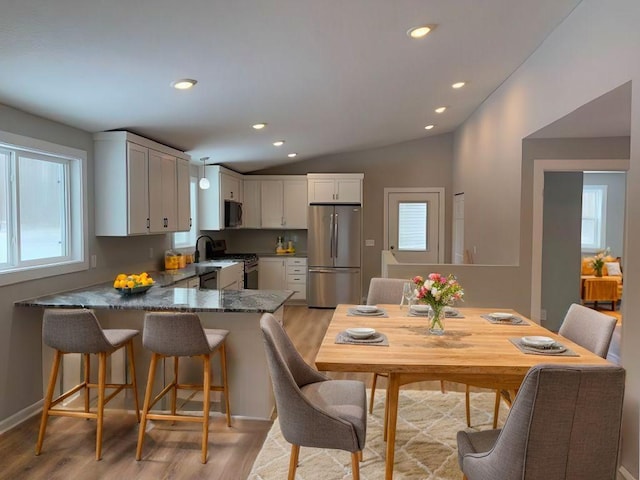 dining area featuring recessed lighting, baseboards, light wood-style floors, and vaulted ceiling