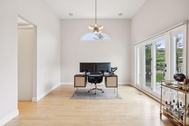 office space with an inviting chandelier, baseboards, and wood finished floors