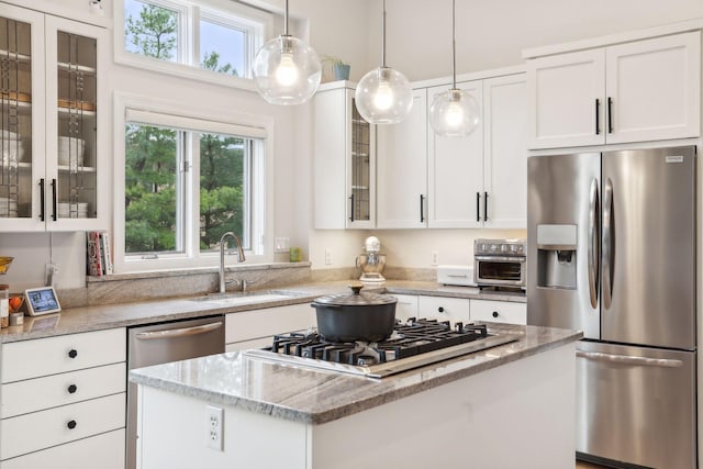 kitchen featuring a kitchen island, a sink, white cabinets, appliances with stainless steel finishes, and light stone countertops