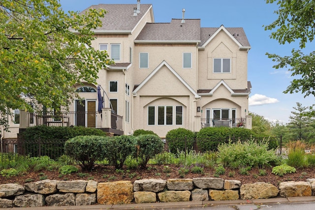 view of front of house featuring a shingled roof, fence, and stucco siding