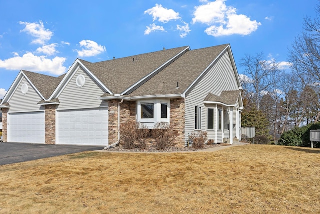 view of front of home with a front yard, an attached garage, driveway, and roof with shingles