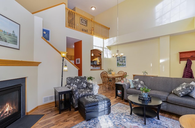 living room featuring a fireplace with flush hearth, visible vents, and wood finished floors