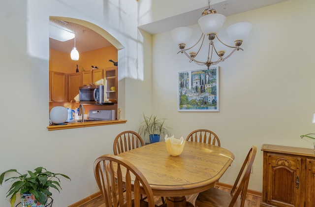 dining room with an inviting chandelier, baseboards, and arched walkways