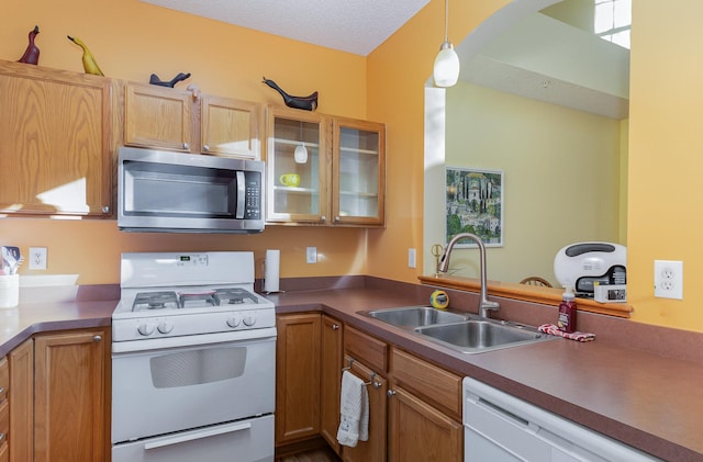 kitchen with arched walkways, decorative light fixtures, white appliances, a sink, and glass insert cabinets