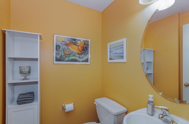 bathroom with a textured ceiling, a sink, toilet, and built in features