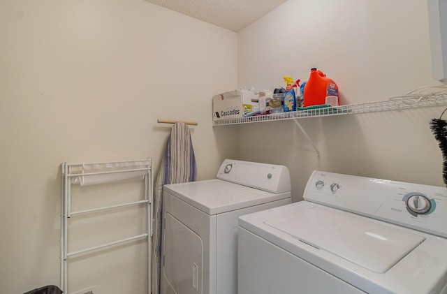 washroom with laundry area, separate washer and dryer, and a textured ceiling