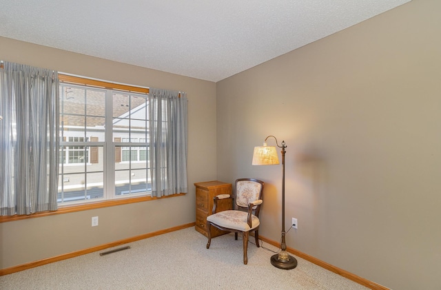 sitting room with light carpet, a textured ceiling, visible vents, and baseboards