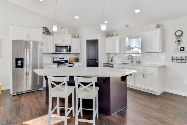 kitchen featuring appliances with stainless steel finishes, white cabinetry, and a kitchen breakfast bar