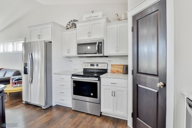 kitchen featuring tasteful backsplash, white cabinets, lofted ceiling, dark wood-style floors, and appliances with stainless steel finishes