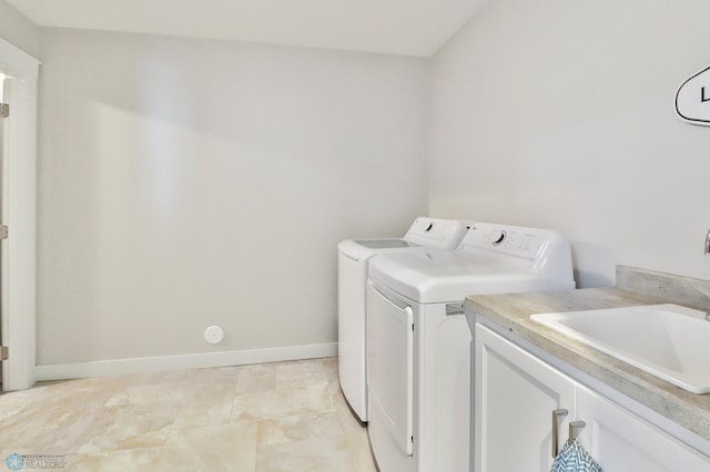 washroom featuring washer and clothes dryer, a sink, cabinet space, and baseboards