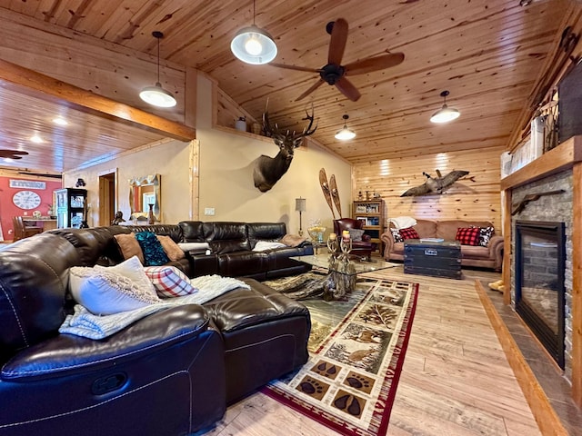 living area featuring ceiling fan, a stone fireplace, wooden ceiling, wooden walls, and wood finished floors