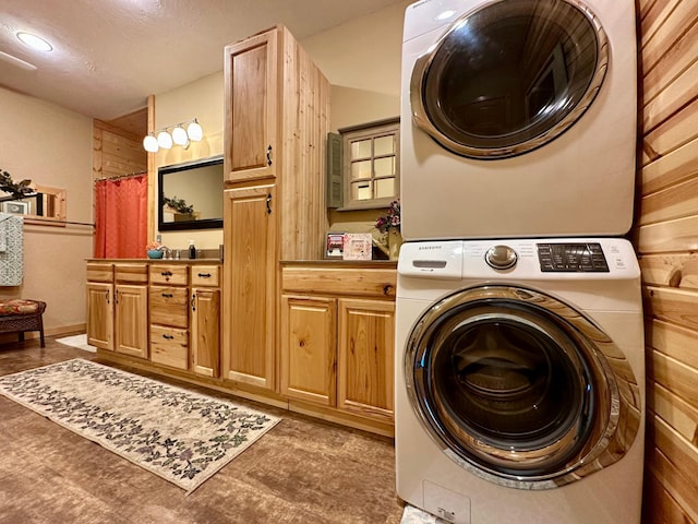 laundry area featuring stacked washer / dryer and cabinet space