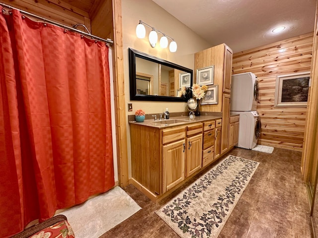 bathroom featuring wooden walls, a shower with shower curtain, vanity, and stacked washer / drying machine